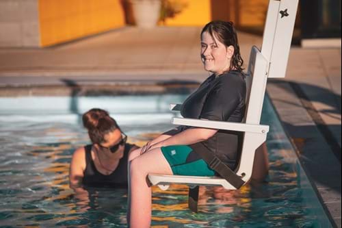 Girl in disabled pool chair getting lowered into the pool.